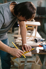 Carpenter working with equipment on wooden table in carpentry shop.