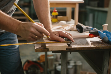 Carpenter working with equipment on wooden table in carpentry shop.