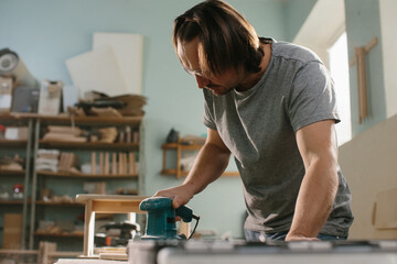 Worker grinds the wood of grinding machine.