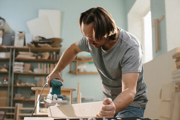 Worker grinds the wood of grinding machine.