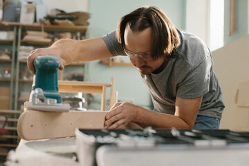 Worker grinds the wood of grinding machine.