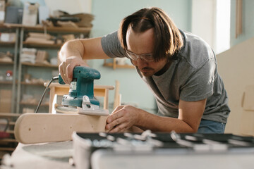 Worker grinds the wood of grinding machine.