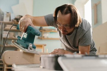 Worker grinds the wood of grinding machine.