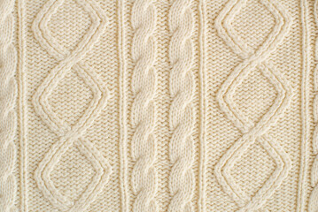 knitted milk sweater with a pattern of braids close-up. Knitted natural wool yarn texture. Texture
