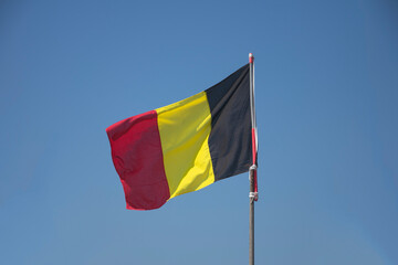 The Belgian flag or Belgian tricolor with a blue sky as background
