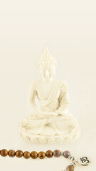 Buddha statue and prayer beads on a light background with copy space. Healing and meditation. Energetic health and relax. Phone background. Soft image style, smartphone format