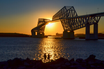 Fototapeta na wymiar Couple looking at huge bridge at sunset 