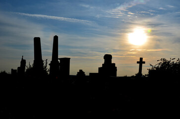 angel is sitting in the cemetery by the church sun is shining in the background. sunset behind...