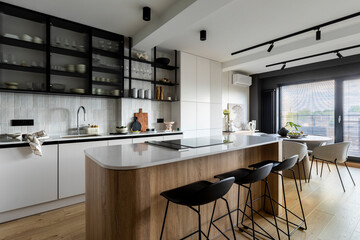 Modern composition of kitchen space with design kitchen island, black hookers, grey table, flowers, furnitures, big window and elegant personal accessories. Stylish home decor. Template. 