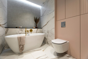 Modern bathroom interior with design marble floor, bathtub, towels, dried flowers in vase and...