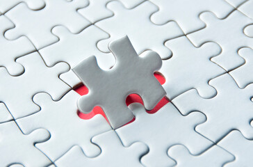 White jigsaw puzzle on red cover background with customizable space for text. Copy space and puzzle concept.