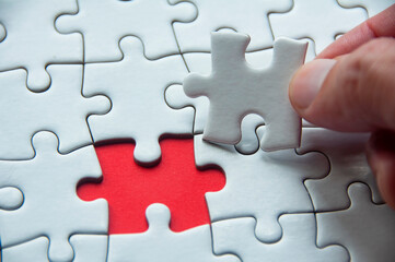 White jigsaw puzzle on red cover background with customizable space for text or idea. Copy space...