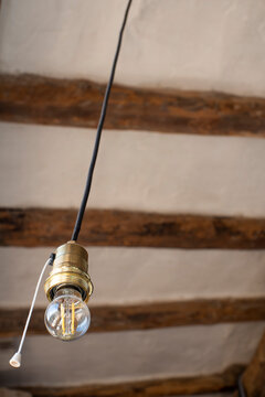 Bombilla colgando, bombilla con interruptor de hilo, bombilla led tipo edison, fondo de bigas de madera, casa de pueblo, r&uacute;stico
