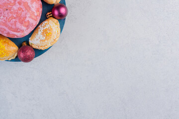 Homemade various biscuits and Christmas baubles on blue board