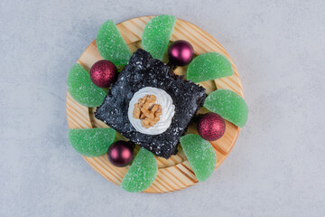 Chocolate brownie with marmalades and baubles on wooden plate
