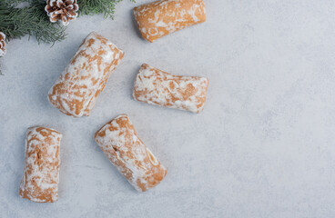 Cookie wrappings next to pine branch and cones on marble background