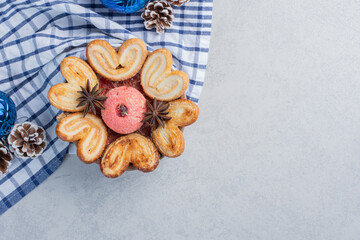 Small platter of cookies adorned with anise, next to christmas decorations on marble background