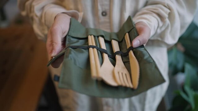 Woman opens set of wooden cutlery on blurred background