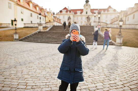 Family walking at Valtice town, Czech Republic. Boy makes a photo of cultural monuments by phone.