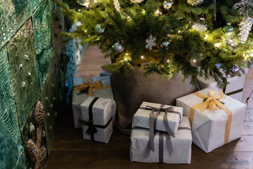 Beautiful Christmas gift boxes on floor near fir tree in room.
