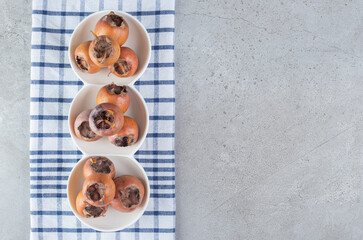 White plates with fresh persimmons on a tablecloth