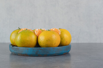 Delicious tangerines in a dark blue plate
