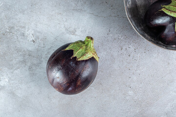 Fresh round purple eggplants on a dark plate