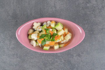 Slices of fresh vegetables in pink bowl