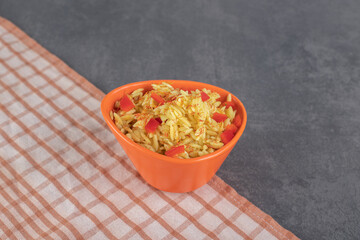 Rice with tomato slices in orange bowl