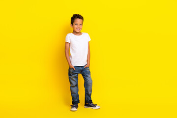 Full length photo of small boy stand wear t-shirt jeans boots isolated on yellow color background © deagreez