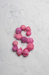 the letter c is laid out with pink flowers on a white background
