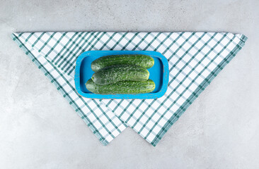 Two fresh cucumbers on a blue board on a tablecloth