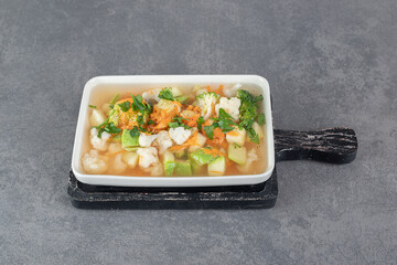 Soup with various vegetable slices on white plate