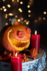 Smiling pumpkin, rowan berries and red candles with bokeh. Close-up