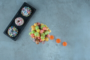 Arrangement of candied snacks with donuts, popcorns, cupcakes and marmelades on marble background