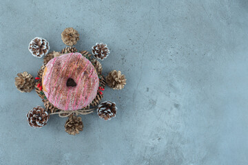 Pine cones around a donut on a wreath on marble background