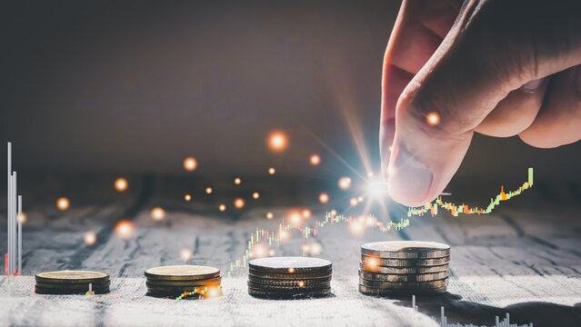 Man hand stacked coins with money saving concept and profit graph business finance in a piggy bank with money boxes for future funds of tourism, home, and retirement on a blurred background.