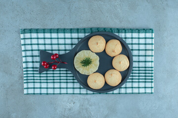 A serving pan with cookies and christmas decorations on a towel on marble background