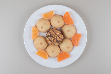 Marmelades and cookies neatly bundled on a white platter on marble background