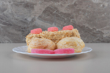 Dessert assortment on a platter, with marmelades and cakes, on marble background