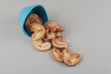 Flaky cookies spilling out of a bowl on marble background