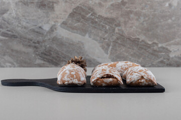 Cookie wrappings and a pine cone on a board on marble background