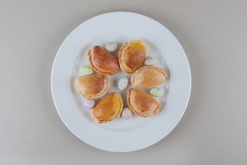 Small buns and candy rocks on a platter on marble background