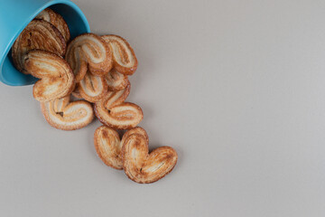 Flaky cookies spilling out of a bowl on marble background