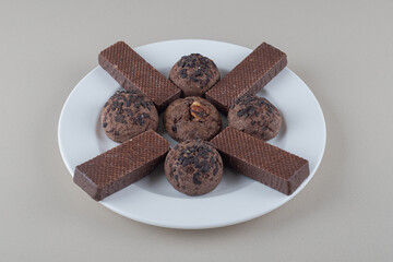 Chocolate coated wafers and chocolate chip cookies on a platter on marble background