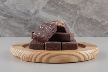 Chocolate wafers bundled together on a wooden platter on marble background