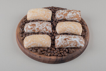 Cookie wrappings and coffee beans on a wooden board on marble background