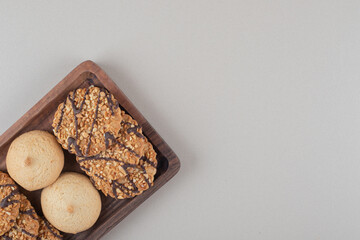 Assortment of cookies on a small wooden tray on marble background