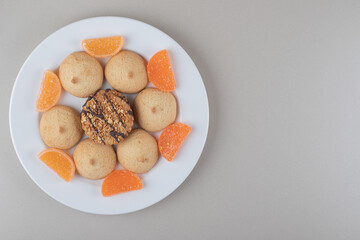 Marmelades and cookies neatly bundled on a white platter on marble background