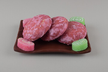 Pink cookies bundled with marmelades on a platter on marble background